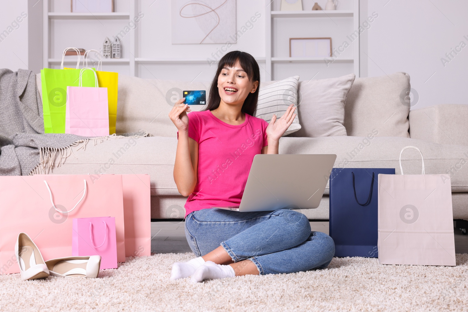 Photo of Internet shopping. Happy woman with credit card, laptop and colorful bags at home