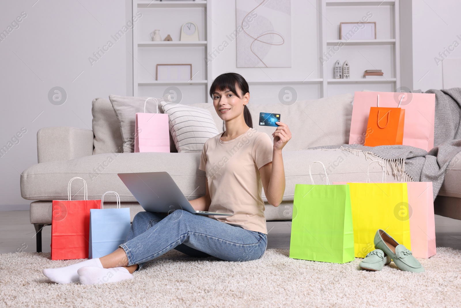 Photo of Internet shopping. Happy woman with credit card, laptop and colorful bags at home