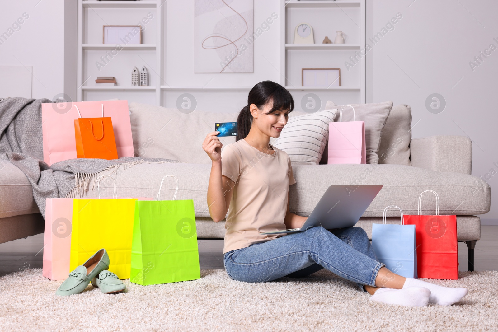 Photo of Internet shopping. Happy woman with credit card, laptop and colorful bags at home