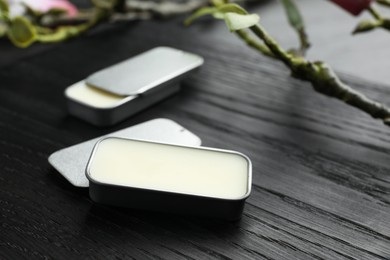 Photo of Natural solid perfume and branch on black wooden table, closeup