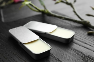 Photo of Natural solid perfume and branch on black wooden table, closeup