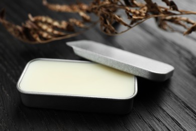 Photo of Natural solid perfume and dry branch on black wooden table, closeup