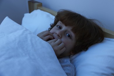 Scared boy lying in bed at night