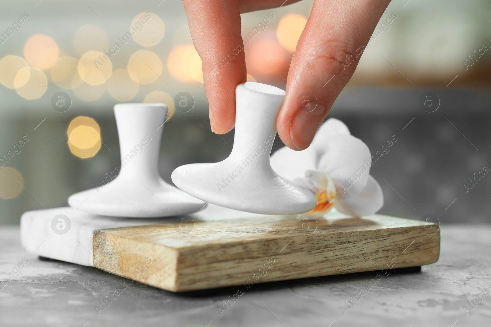 Photo of Woman with spa stone at grey table, closeup