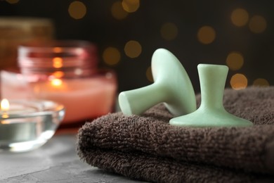 Photo of Spa stones, towel and burning candles on grey table, closeup