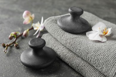 Photo of Spa stones, towels and orchid flowers on grey table, closeup