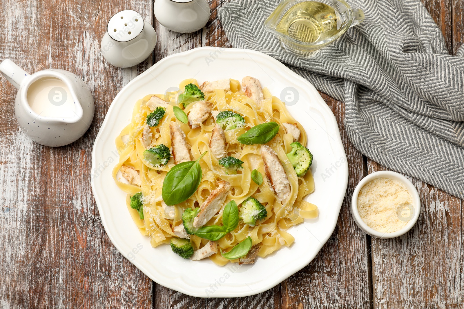 Photo of Delicious pasta Alfredo with chicken served on wooden table, flat lay