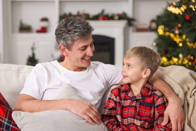 Photo of Father and son in pajamas on sofa at home. Christmas morning