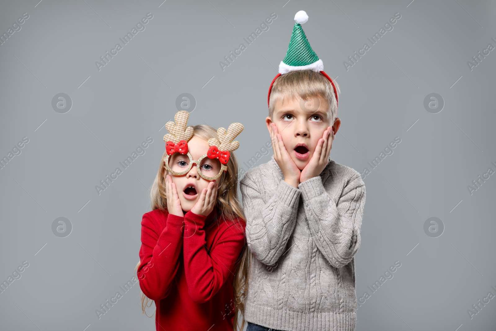 Photo of Funny children in Christmas accessories on grey background