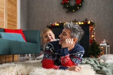 Photo of Dad and son near decorated fireplace at home. Christmas season