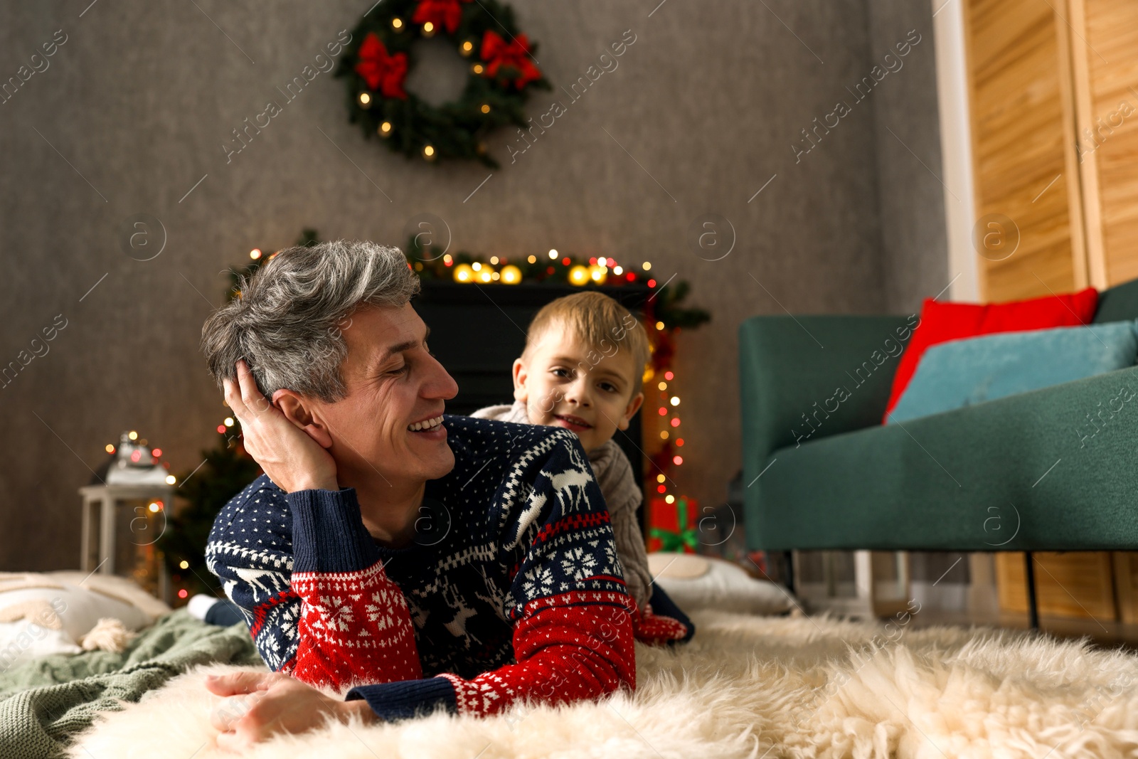 Photo of Dad and son near decorated fireplace at home. Christmas season