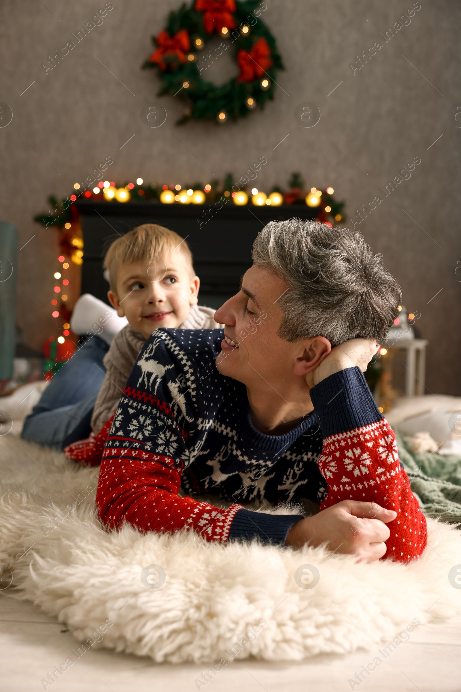 Photo of Dad and son near decorated fireplace at home. Christmas season