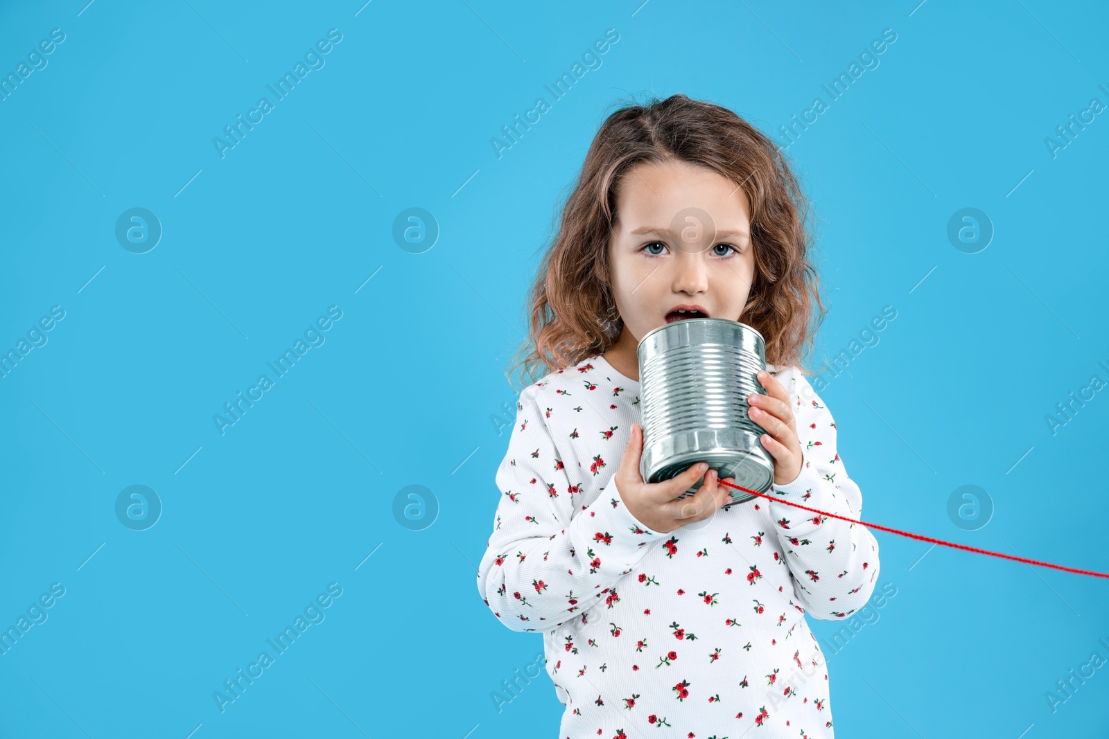 Photo of Girl using tin can telephone on blue background. Space for text