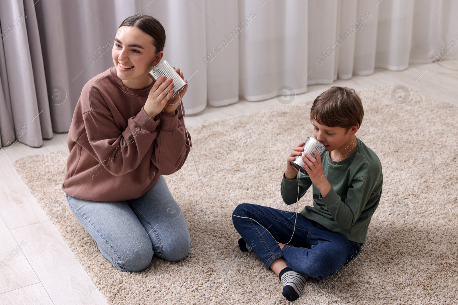 Photo of Woman and boy talking on tin can telephone indoors