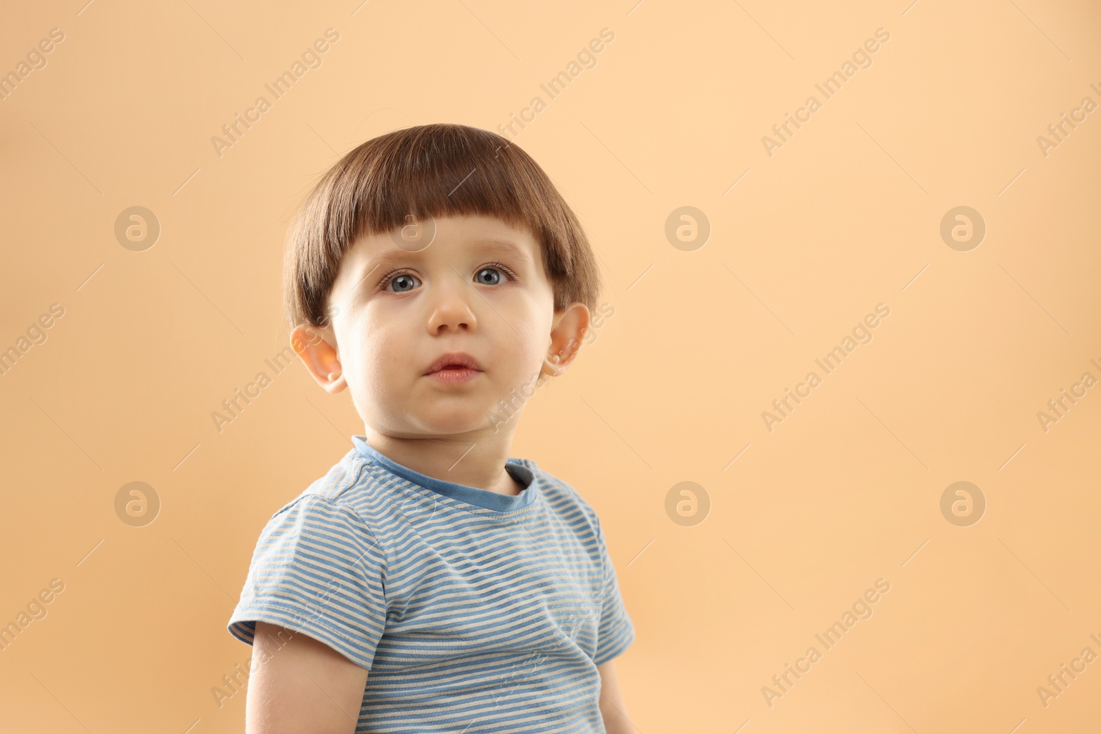 Photo of Portrait of cute little boy on beige background. Space for text