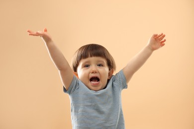 Photo of Portrait of emotional little boy on beige background