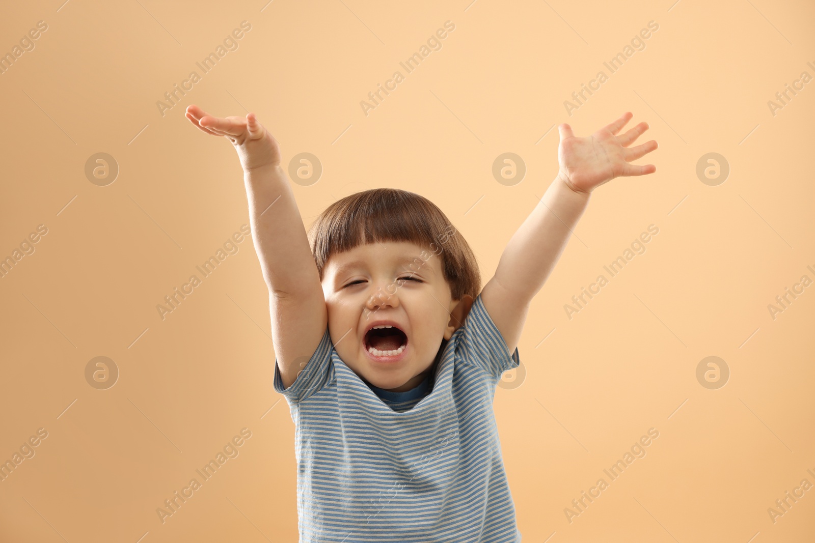 Photo of Portrait of emotional little boy on beige background