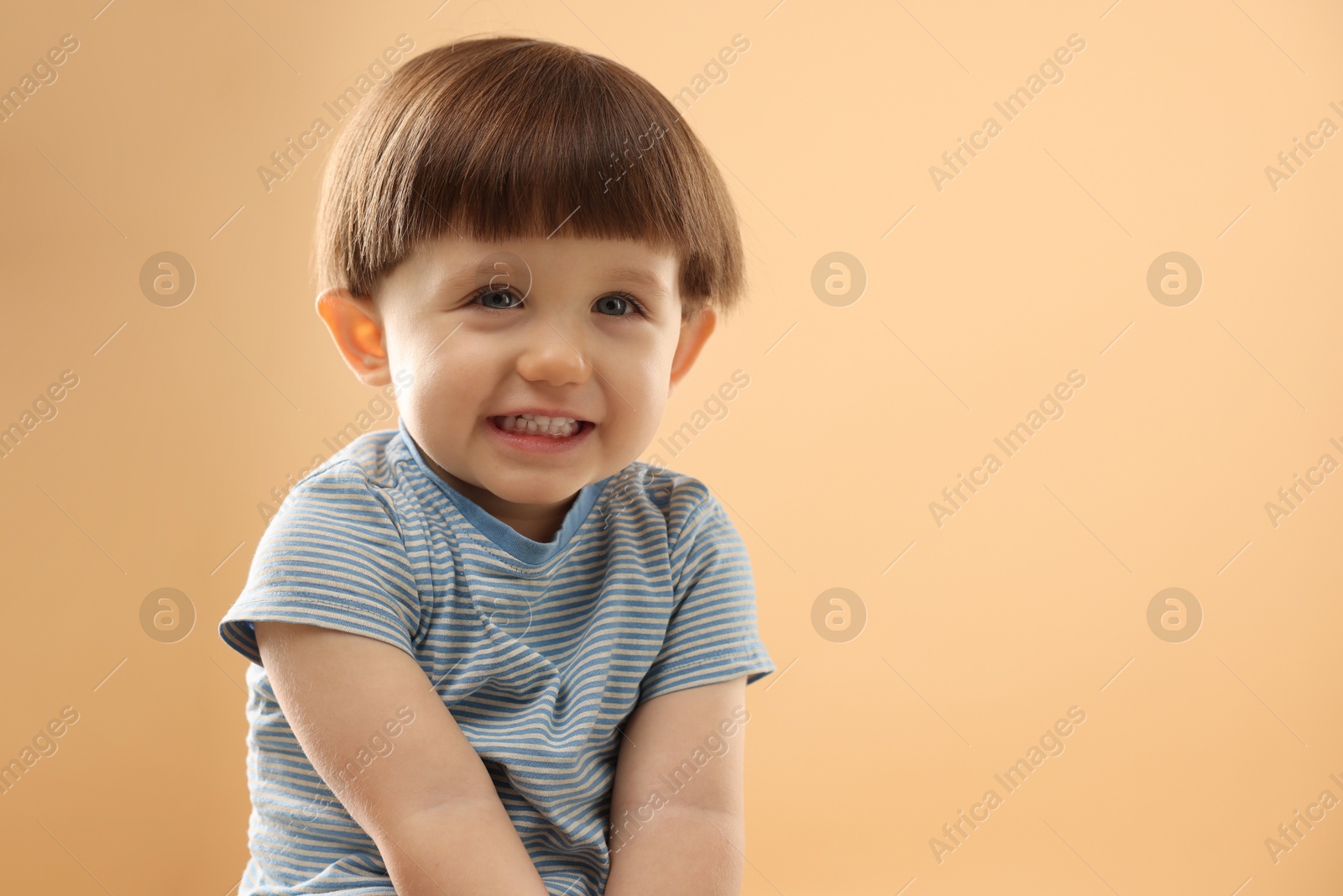 Photo of Portrait of smiling little boy on beige background. Space for text