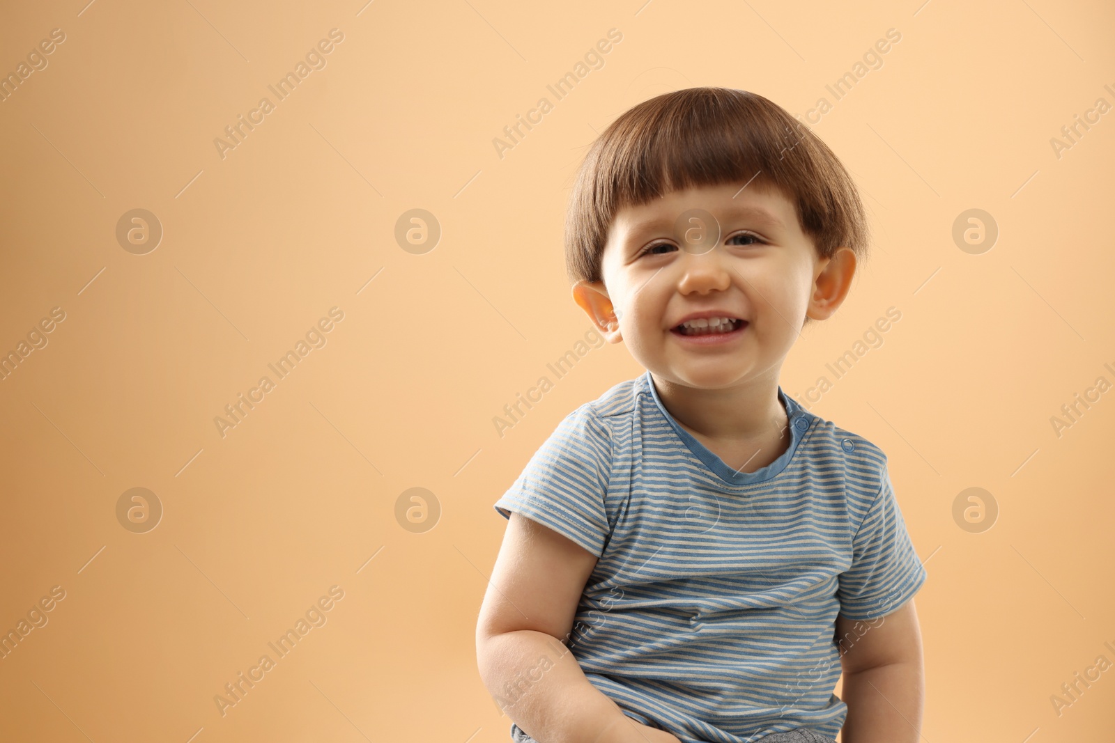 Photo of Portrait of smiling little boy on beige background. Space for text