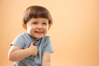 Photo of Portrait of happy little boy on beige background. Space for text