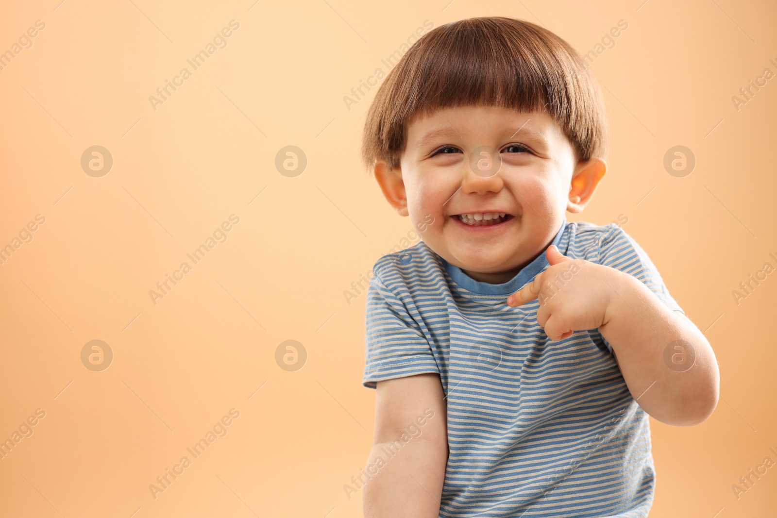 Photo of Portrait of happy little boy on beige background. Space for text