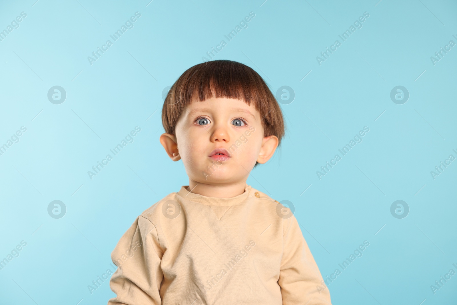 Photo of Portrait of cute little boy on light blue background