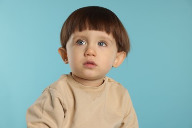 Photo of Portrait of cute little boy on light blue background