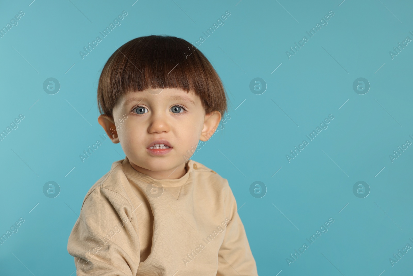 Photo of Portrait of cute little boy on light blue background. Space for text