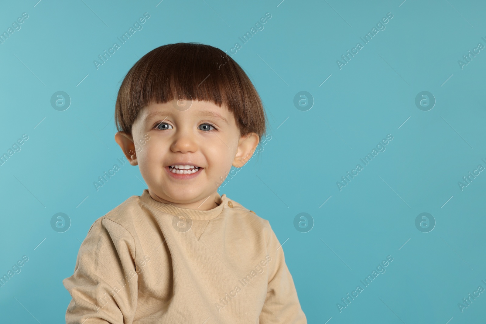 Photo of Portrait of happy little boy on light blue background. Space for text