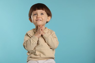 Photo of Portrait of happy little boy on light blue background. Space for text