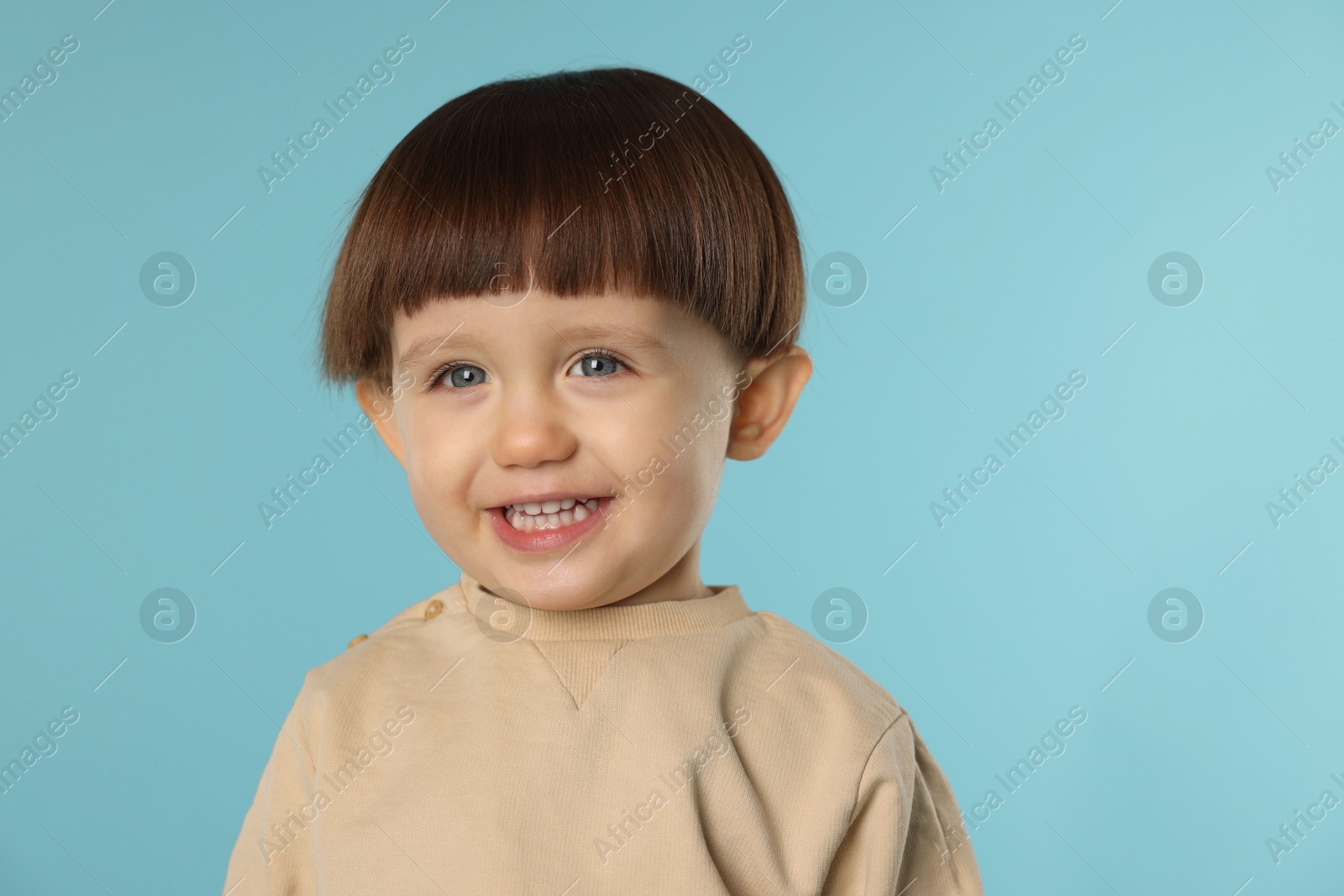 Photo of Portrait of happy little boy on light blue background