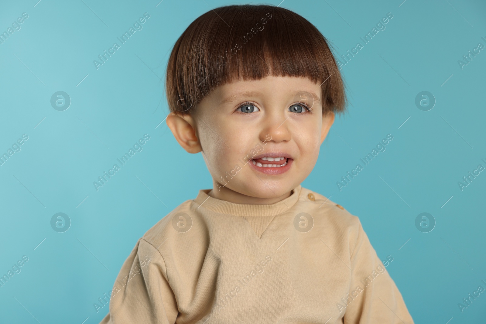 Photo of Portrait of happy little boy on light blue background