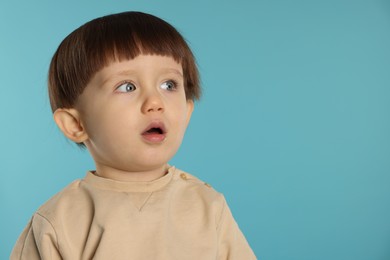 Photo of Portrait of cute little boy on light blue background. Space for text