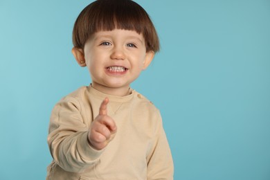 Photo of Portrait of cute little boy on light blue background. Space for text