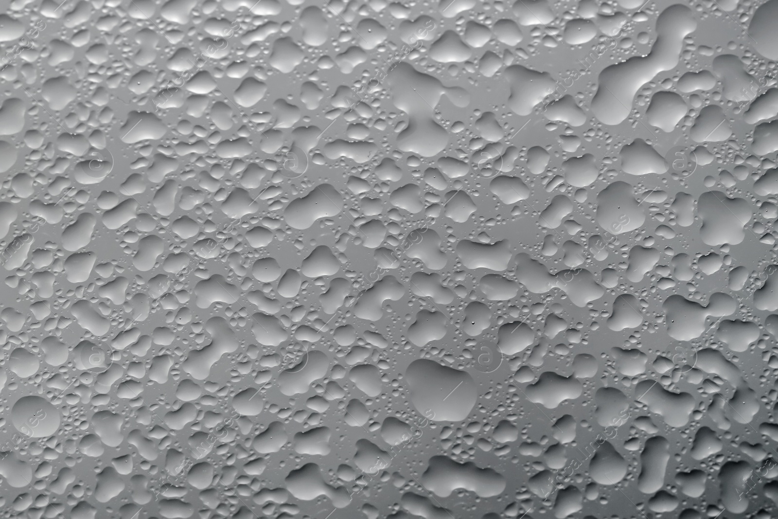 Photo of Water drops on grey glass surface, top view