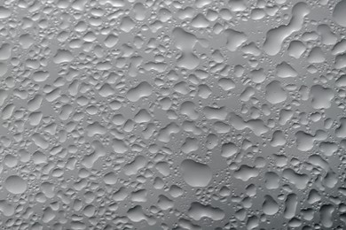 Photo of Water drops on grey glass surface, top view