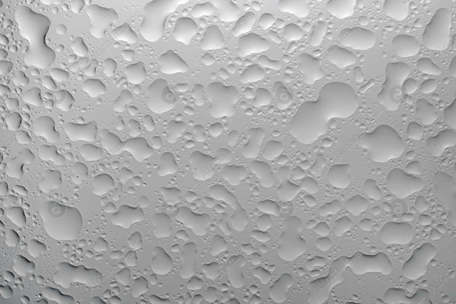 Photo of Water drops on light grey glass surface, top view