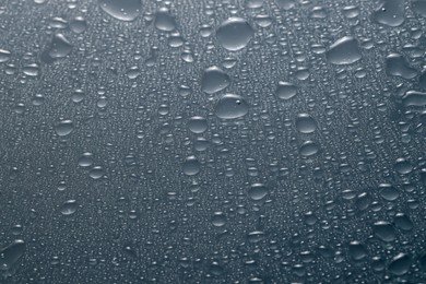 Photo of Water drops on grey glass surface, top view