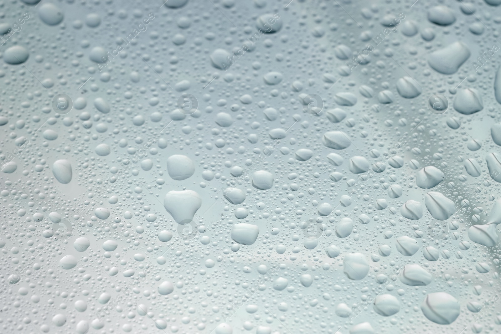 Photo of Water drops on light glass surface, closeup