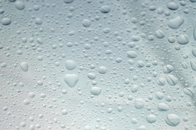 Photo of Water drops on light glass surface, closeup