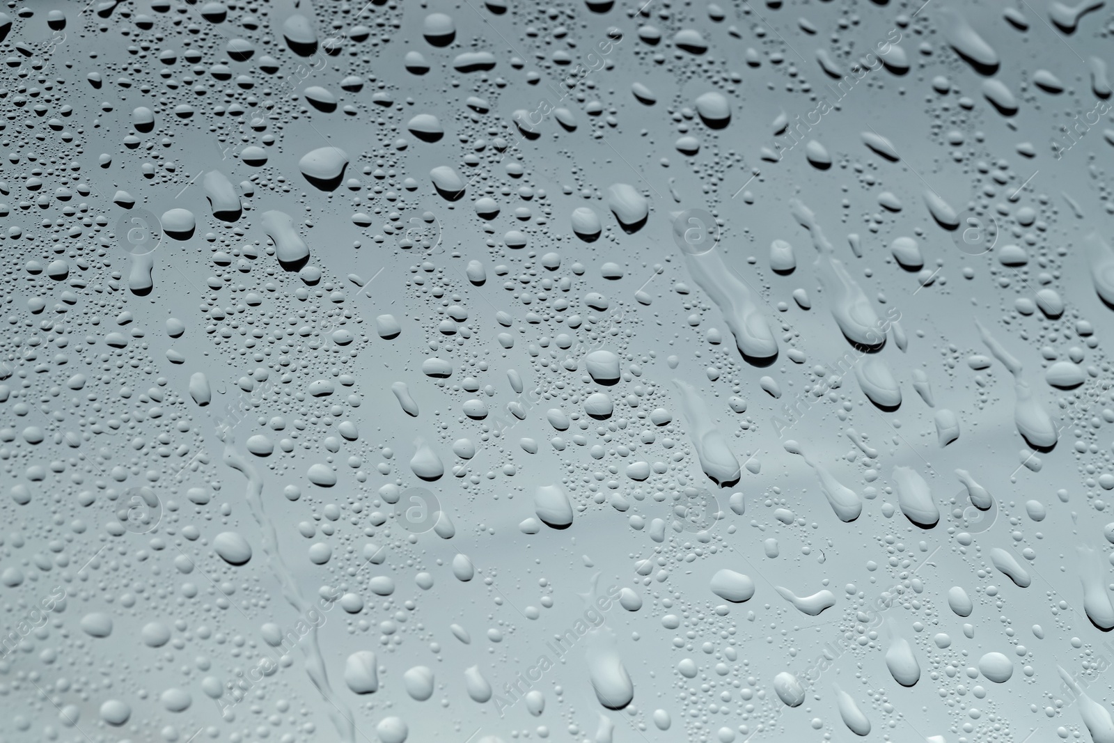 Photo of Water drops on grey glass surface, closeup