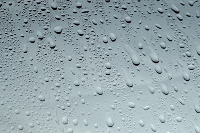 Photo of Water drops on grey glass surface, closeup