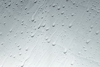 Photo of Water drops on grey glass surface, closeup