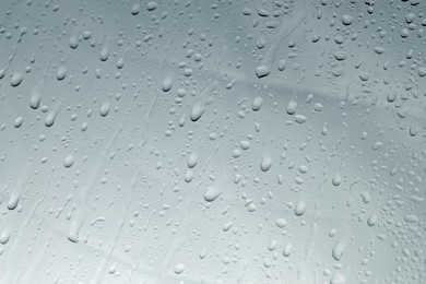 Photo of Water drops on grey glass surface, closeup