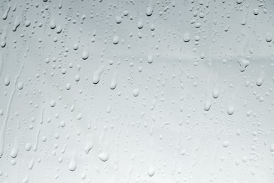 Photo of Water drops on light glass surface, top view