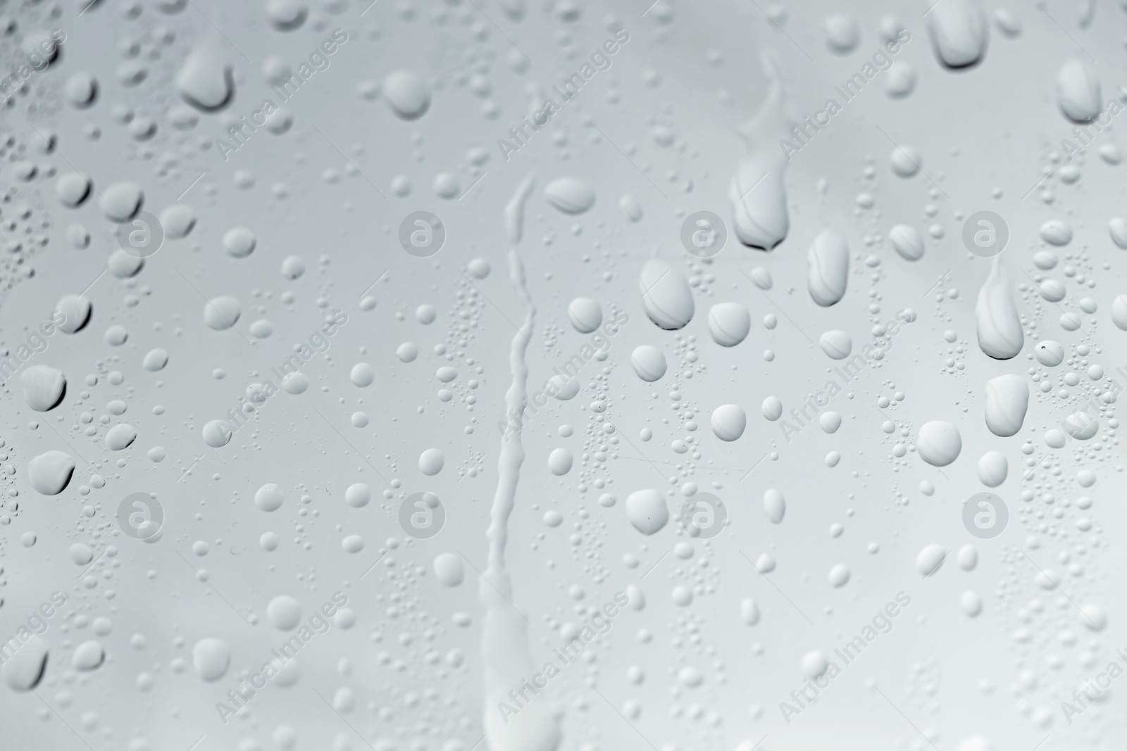 Photo of Water drops on light glass surface, closeup