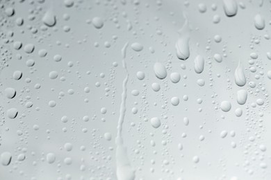 Water drops on light glass surface, closeup