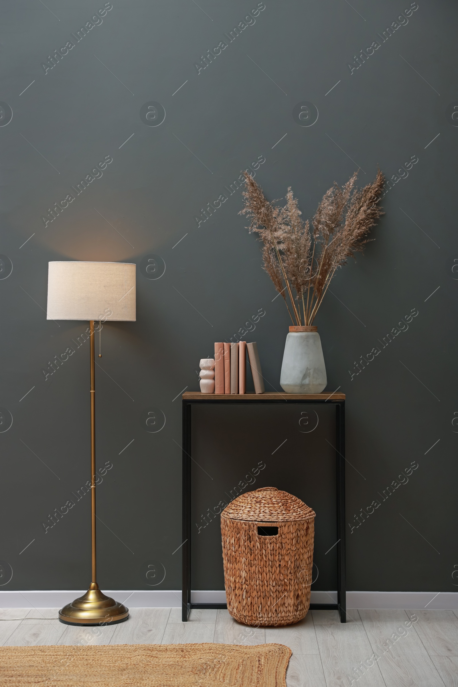 Photo of Console table with decor and lamp near grey wall in room. Interior design