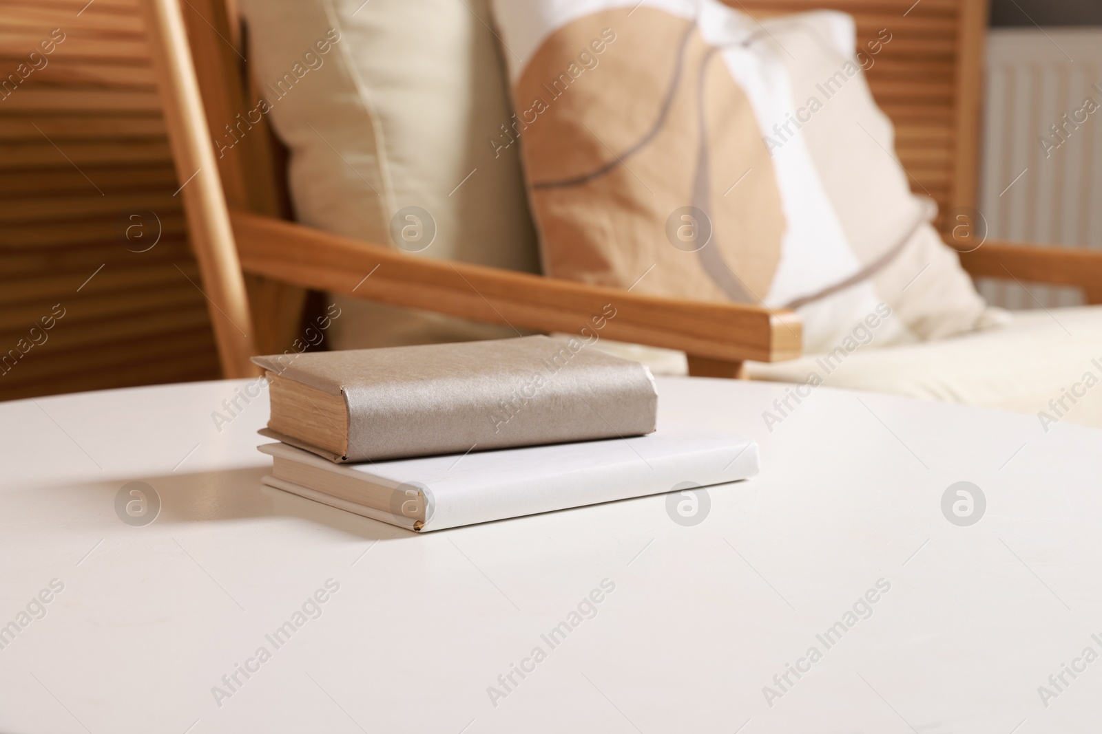 Photo of Stylish coffee table with books near armchair at home, closeup