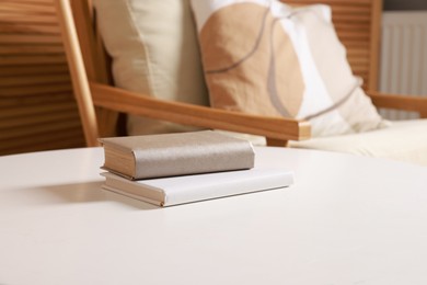 Photo of Stylish coffee table with books near armchair at home, closeup